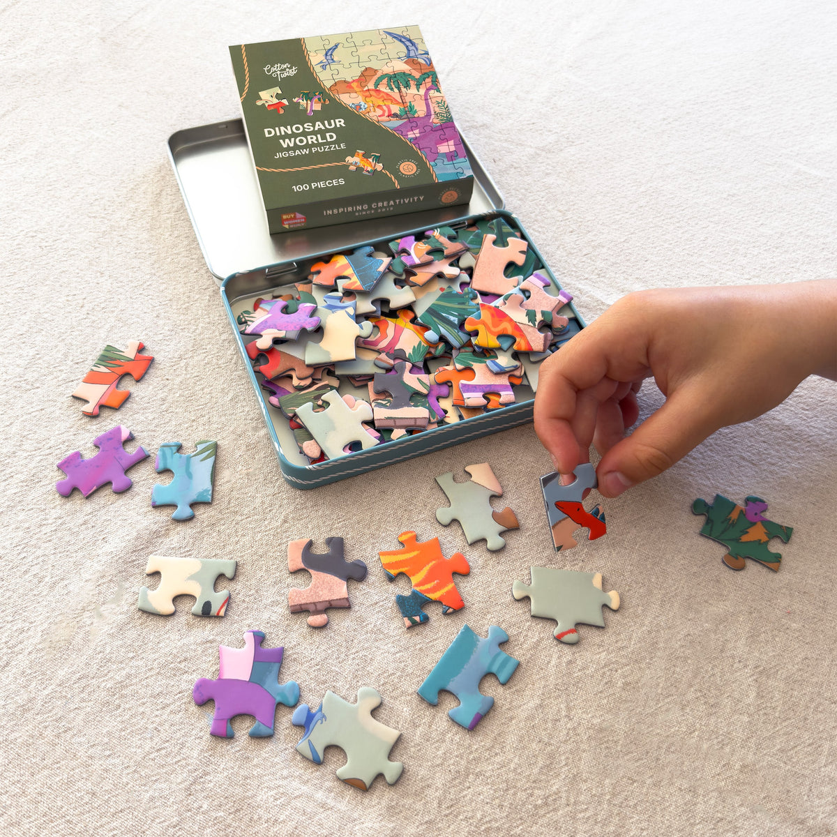 Dinosaur World jigsaw pieces being sorted from the open tin