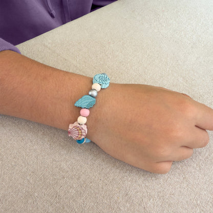Child wearing a seashell bead bracelet made with the Cotton Twist Seashell Beading Kit