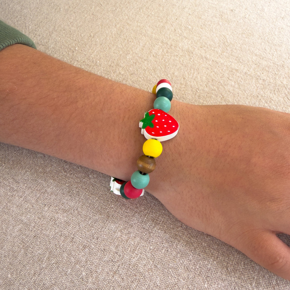 Child wearing a strawberry bead bracelet made with the Cotton Twist Strawberry Beading Kit