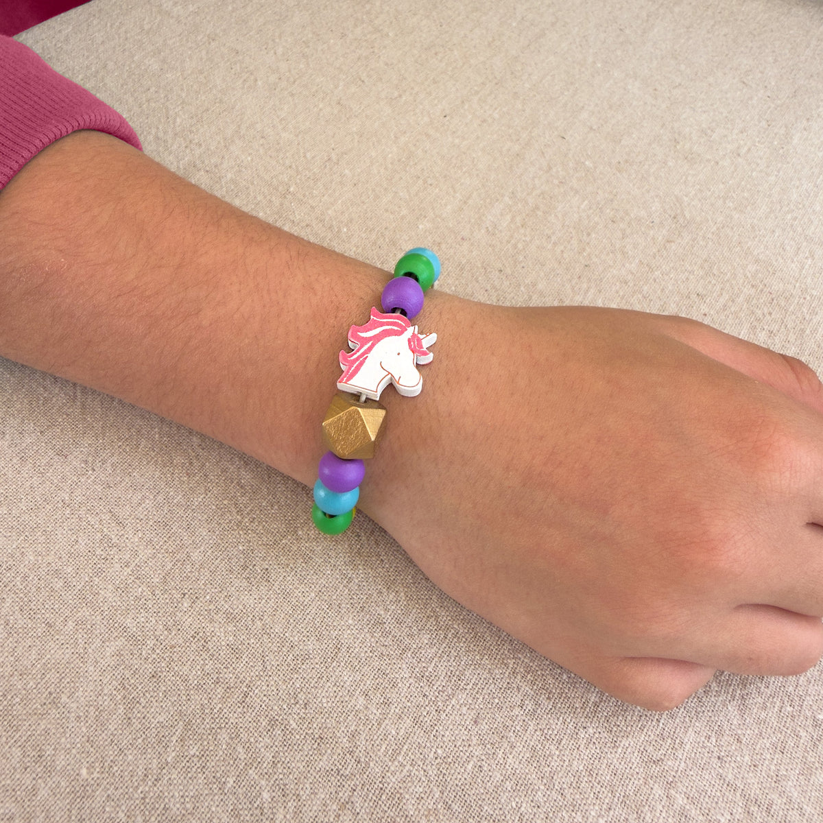 Child wearing a unicorn bead bracelet made with the Cotton Twist Unicorn Beading Kit