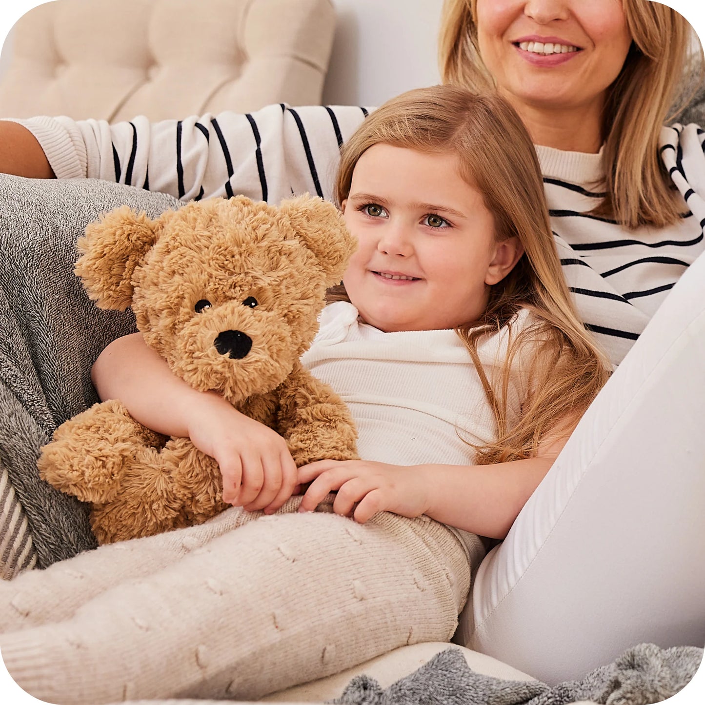 Child cuddling a Warmies brown curly bear heatable lavender plush toy