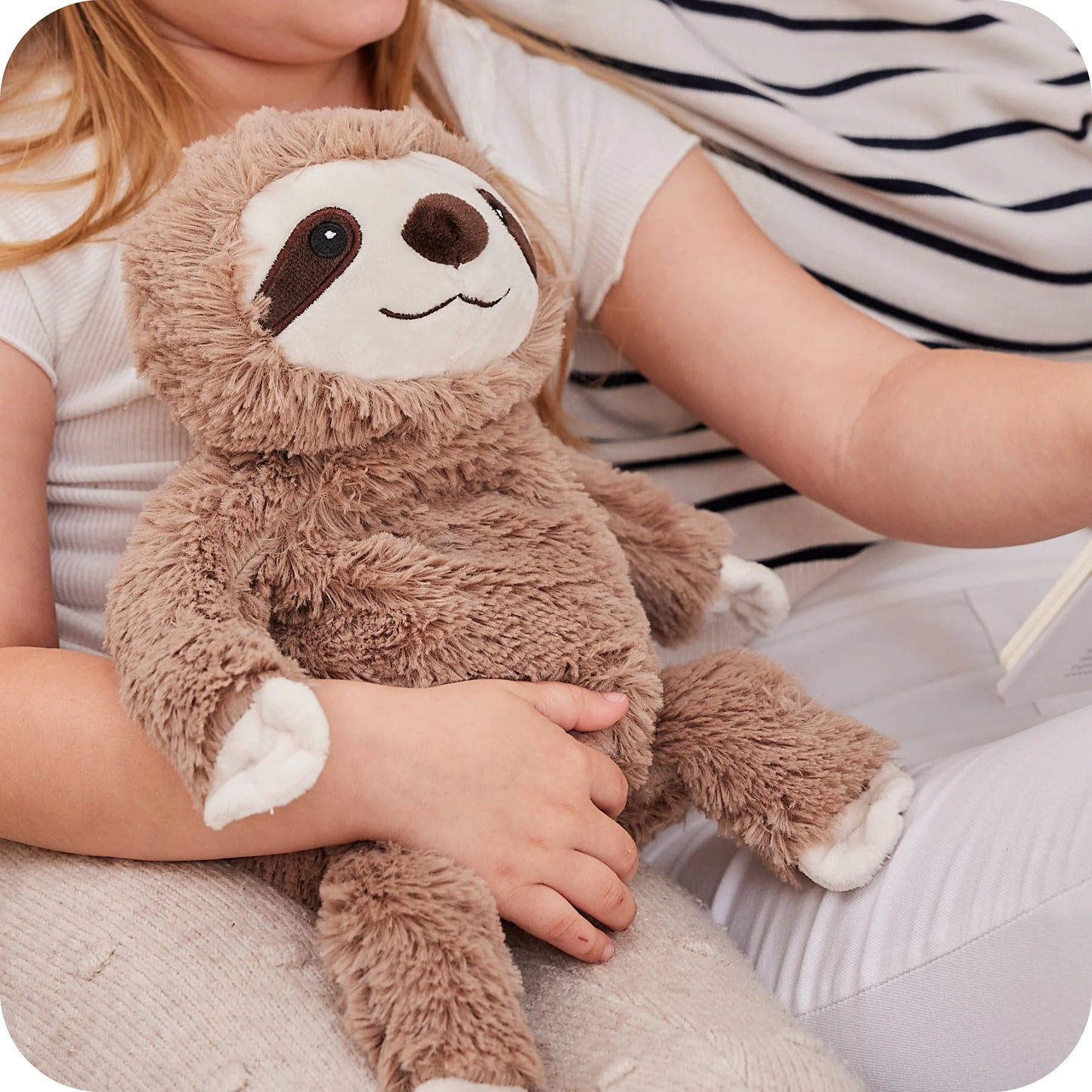 Child holding a Warmies Junior sloth microwavable lavender plush toy
