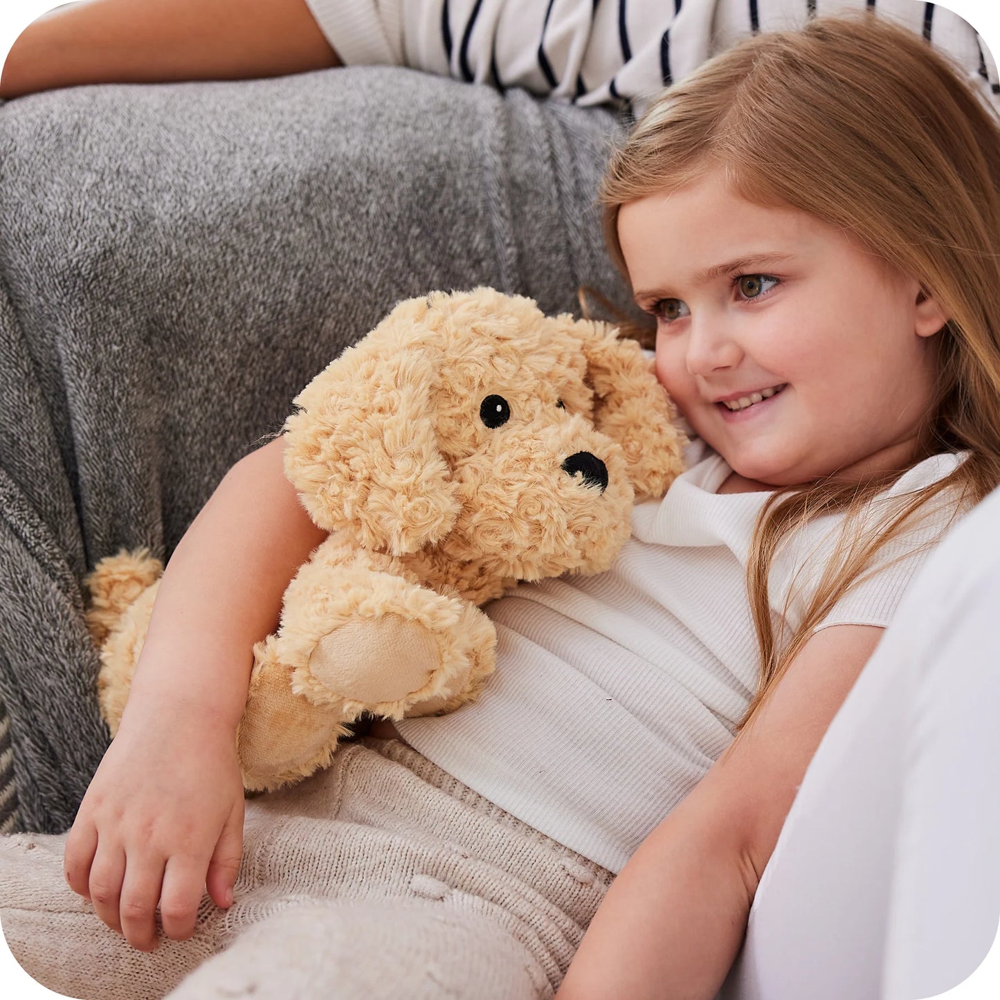 Child holding a Warmies cockapoo microwavable lavender plush toy