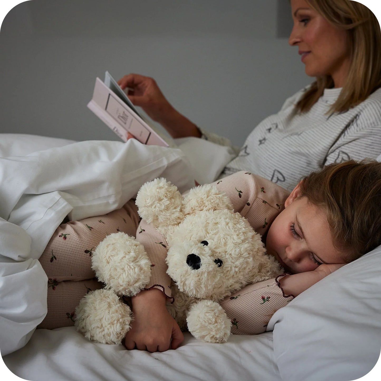 Child at bedtime with a Warmies cream curly bear heatable lavender plush toy