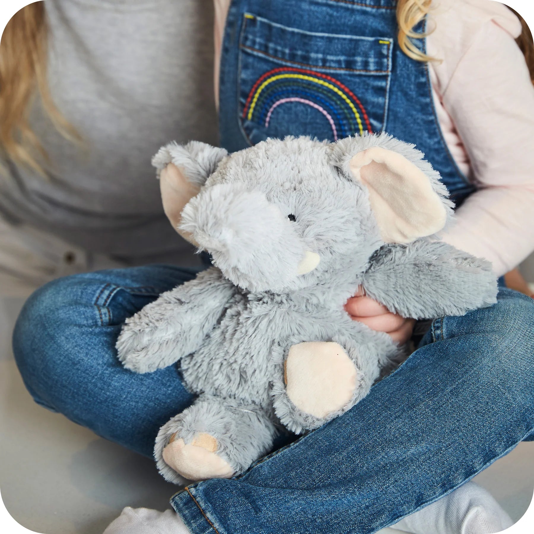 Child holding a Warmies grey elephant microwavable lavender plush toy