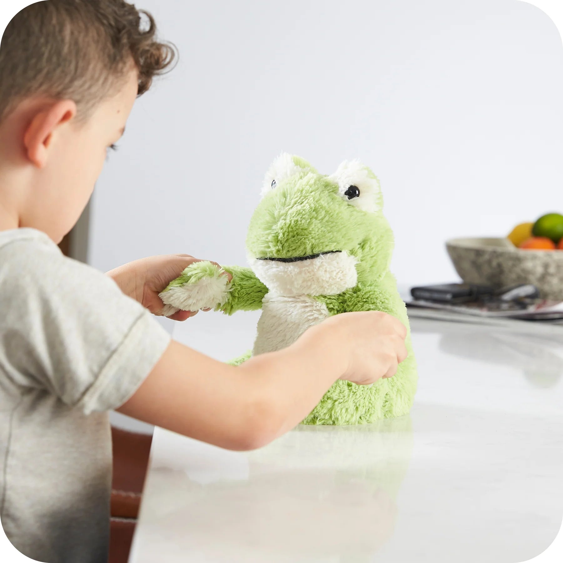 Child playing with a Warmies green frog microwavable lavender plush toy