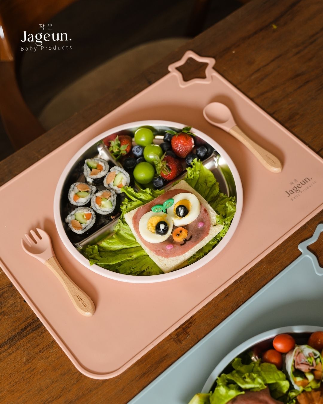 Jageun stainless steel divided plate with sushi and salad on a pink placemat