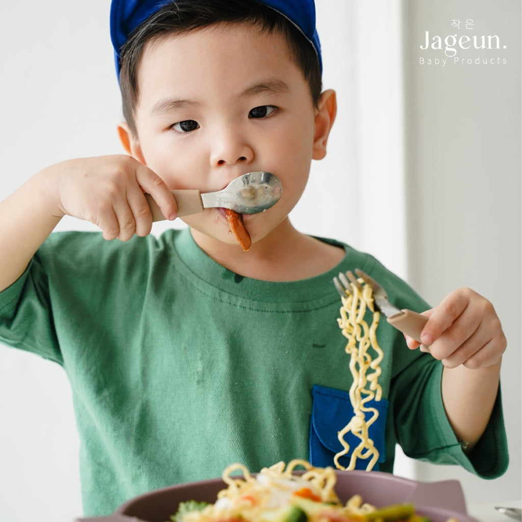 Child eating noodles with a Jageun stainless spoon and fork